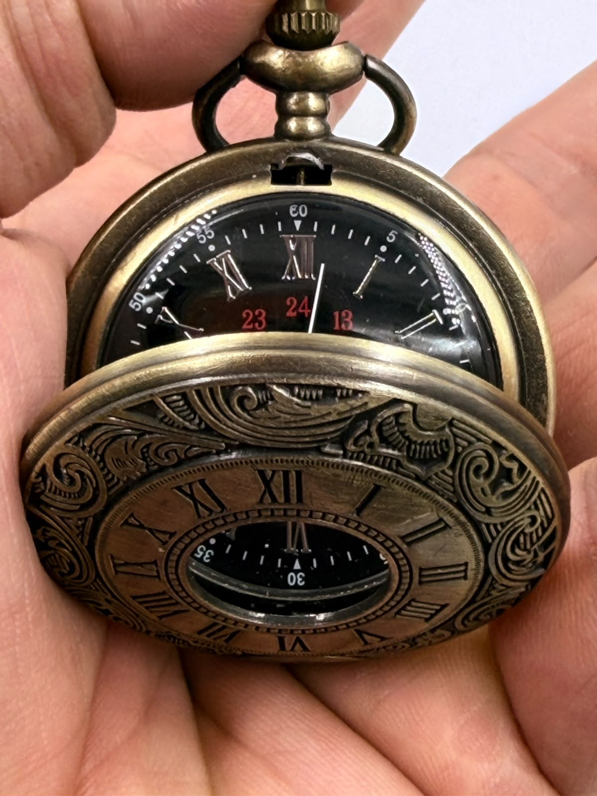 Vintage bronze pocket watch with chain on dark wooden surface