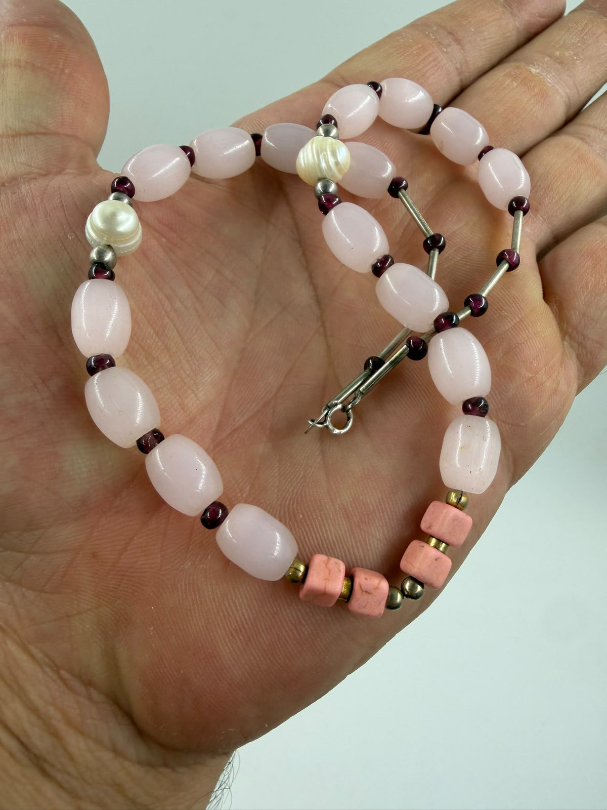 Natural rose quartz oval bracelet in hand showing translucent petal-pink color and smooth finish