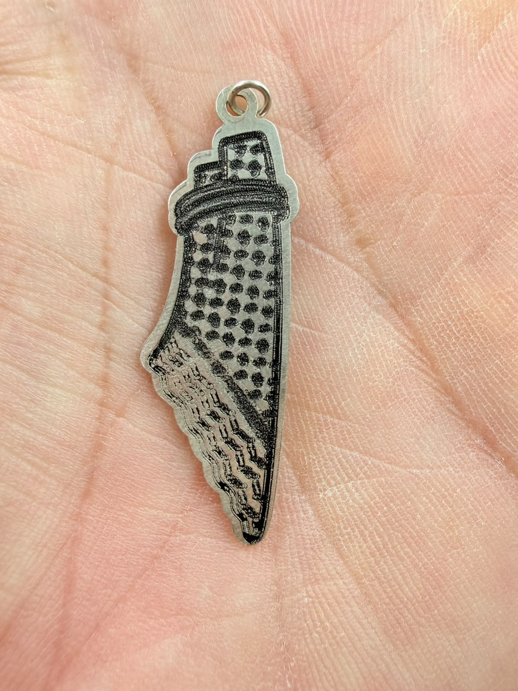 Palestine map pendant held in hand - front showing keffiyeh pattern detail