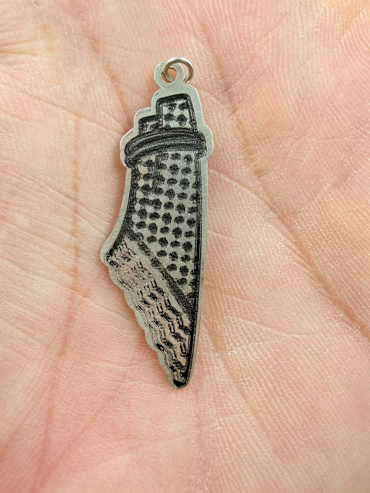 Palestine map pendant held in hand - front showing keffiyeh pattern detail
