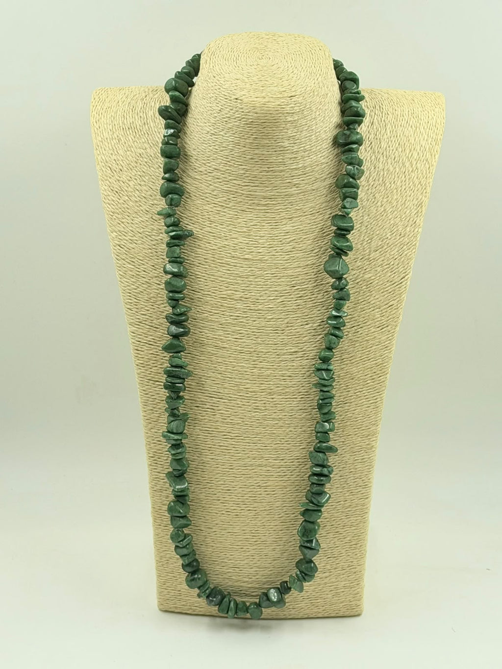 Green aventurine chip necklace coiled on white surface