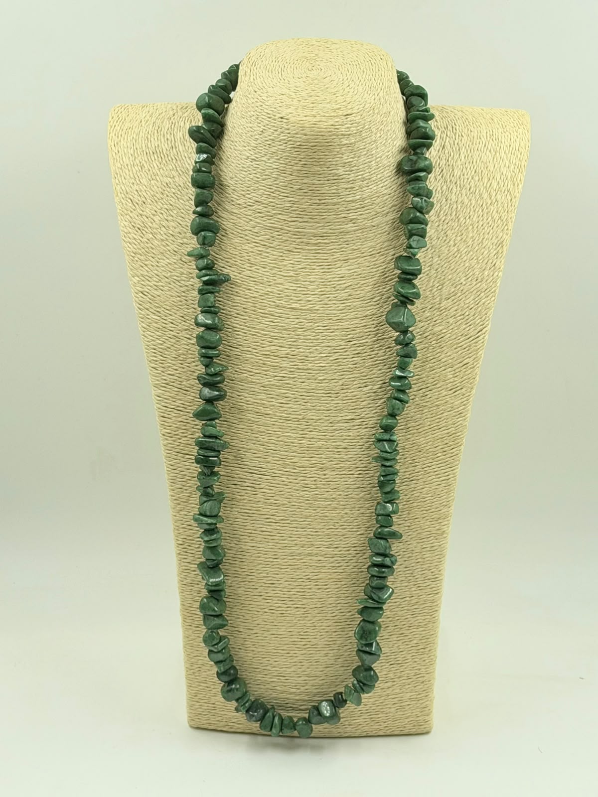 Green aventurine chip necklace coiled on white surface