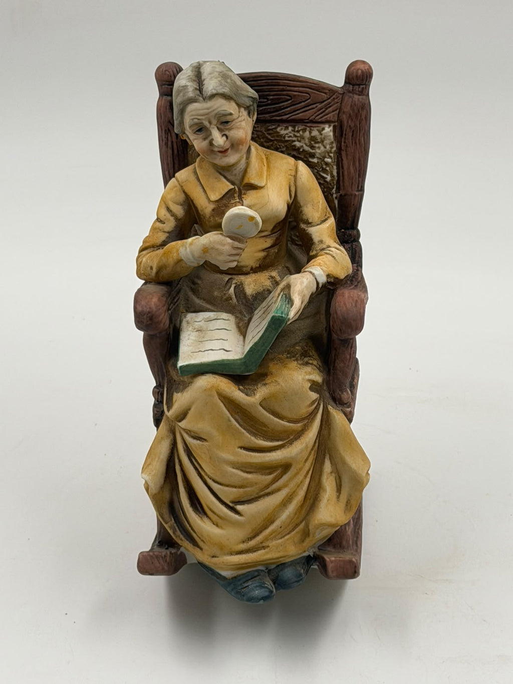 Vintage resin grandma reading figurine close-up of face and magnifying glass detail