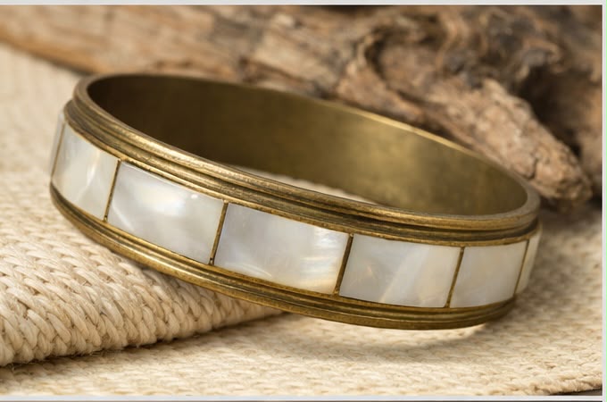 Vintage brass mother of pearl bangle bracelet on woven surface lifestyle shot
