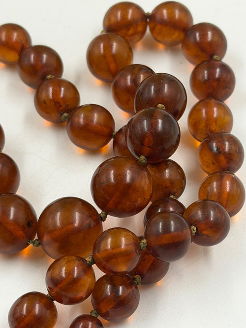 Amber necklace held in hand showing bead detail and clasp