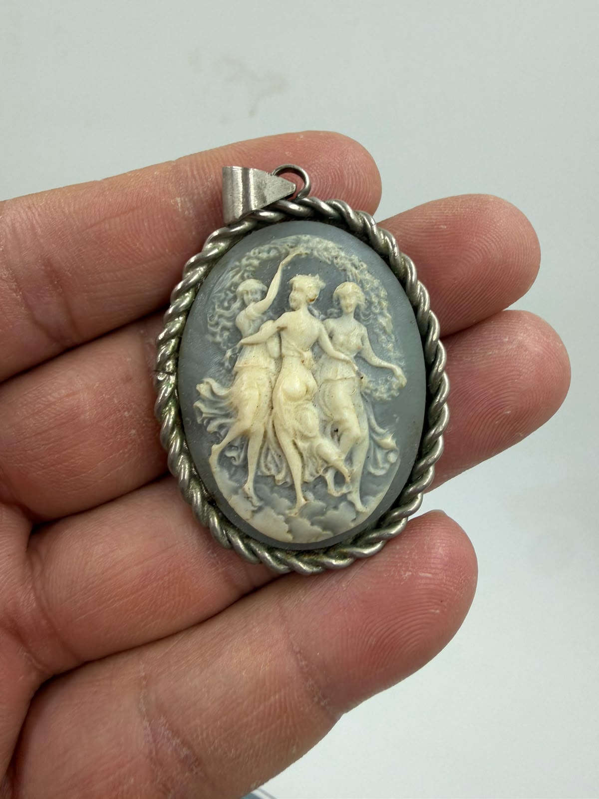925 silver Three Graces cameo pendant held in hand front showing twisted rope frame and blue-grey cameo