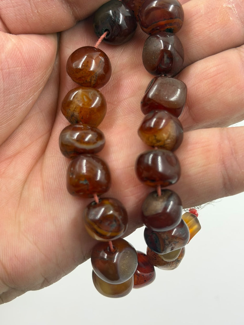 Natural red agate tumbled bracelet macro showing individual bead texture polish and color variation